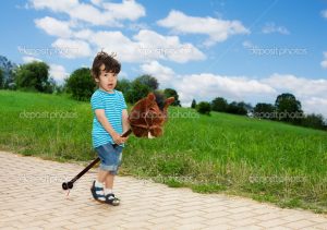 kid playing with horse stick pretending to be a cowboy
